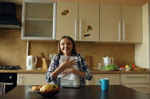 Attractive happy woman recieve good news reading letter in the kitchen while have breakfast at home